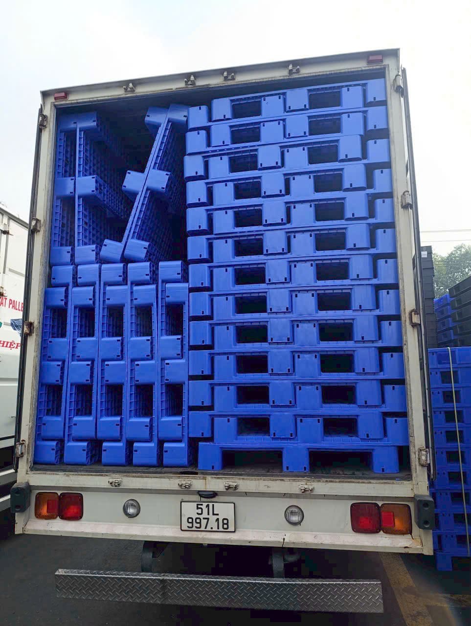 Thùng xe tải chất đầy pallet nhựa màu xanh dương xếp gọn gàng