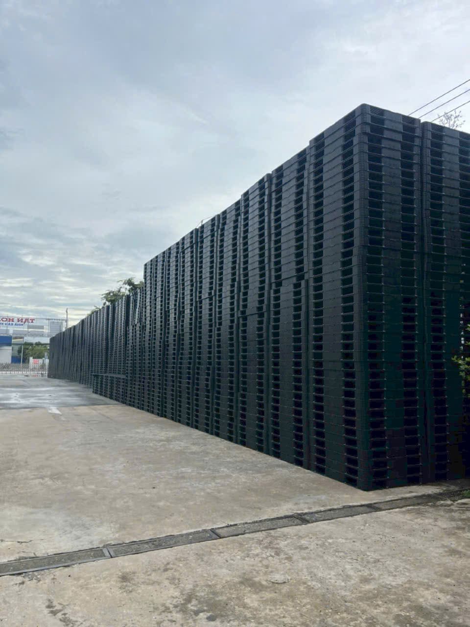 Dãy pallet nhựa màu đen xếp chồng dài vô tận dọc đường đi