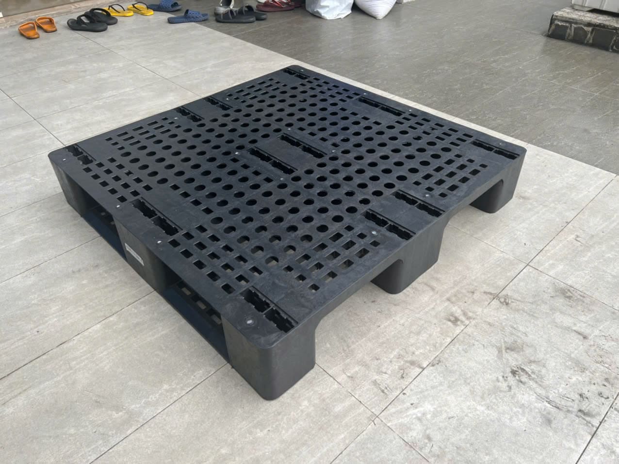 Pallet nhựa màu đen 9 chân gù mặt lưới lỗ tròn lót sàn kho