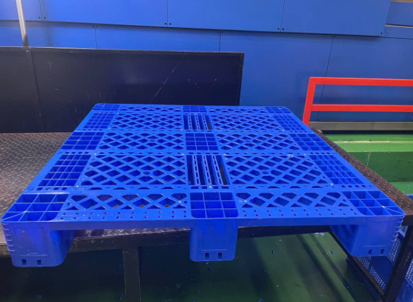 Pallet nhựa màu xanh nan chéo chịu tải nặng đặt trên bàn nâng